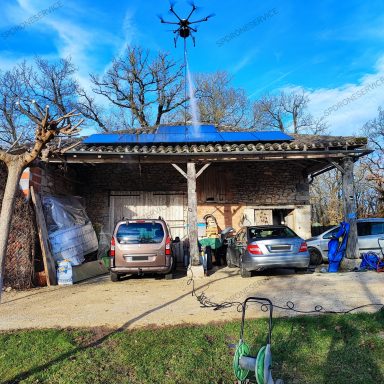 Nettoyage panneaux photovoltaïques par drone Une maison avec panneaux solaires, voitures garées et un drone en vol.